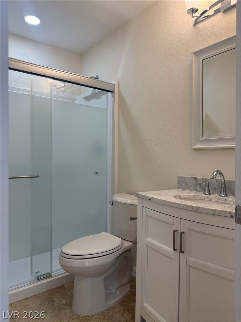 A well-appointed bathroom features a contemporary vanity with a marble counter, sleek fixtures, and a glass-enclosed shower.