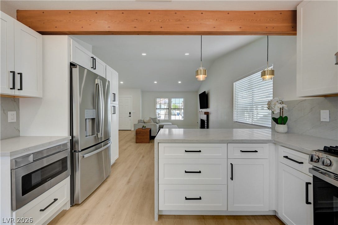 3131 White Rose Way, Henderson, NV 89014 A well-lit kitchen with sleek appliances and light wood flooring opens to a spacious living area.