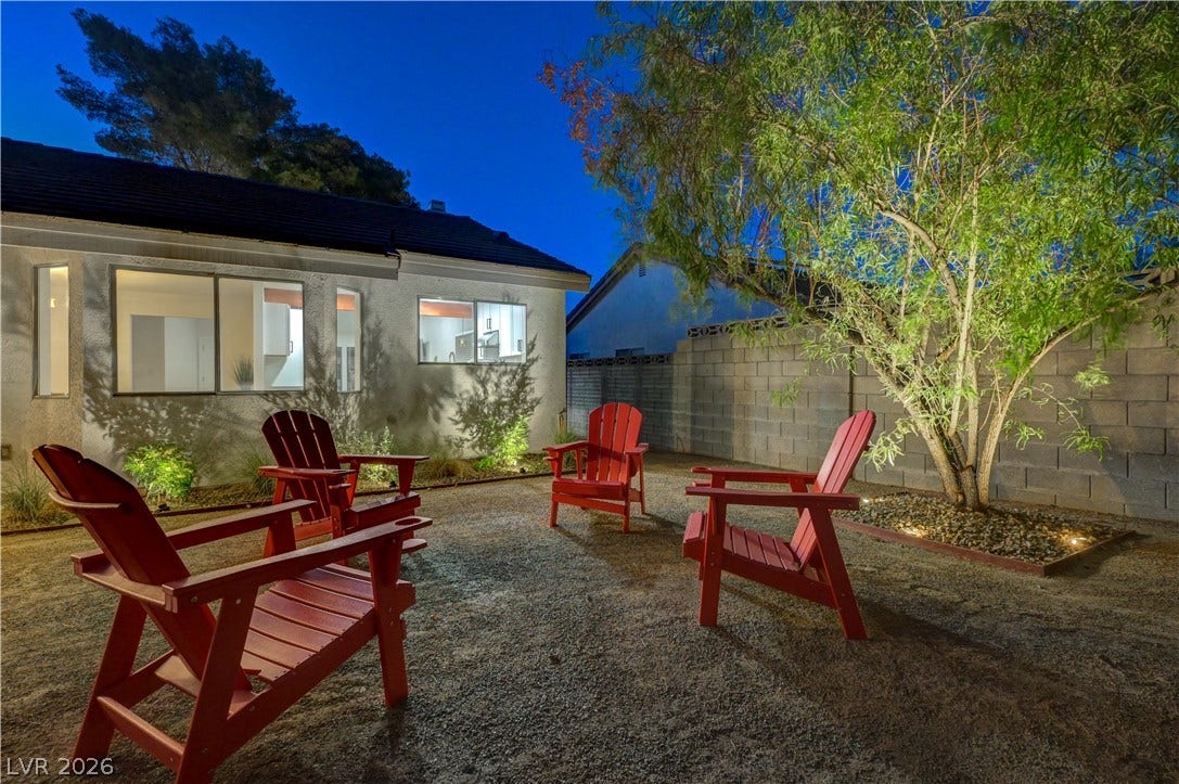3131 White Rose Way, Henderson, NV 89014 A private, gravel backyard illuminated by warm outdoor lighting, perfect for evening gatherings.