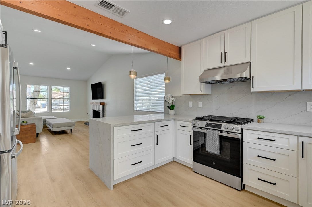 3131 White Rose Way, Henderson, NV 89014 A pristine open-concept kitchen flows seamlessly into the living space, featuring white cabinetry and light wood flooring.