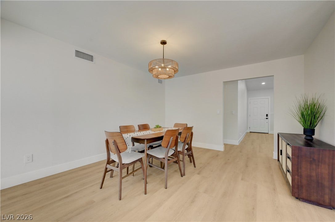 3131 White Rose Way, Henderson, NV 89014 A contemporary dining room with light hardwood floors flows into an inviting entryway.