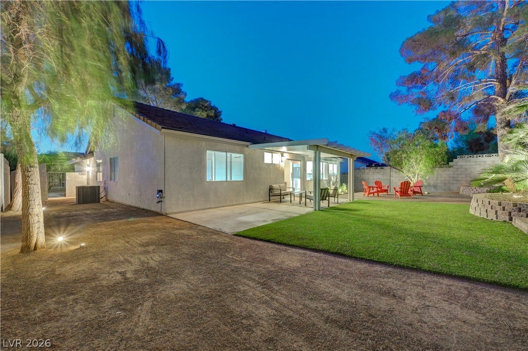 3131 White Rose Way, Henderson, NV 89014 An inviting backyard oasis offers both covered patio lounging and open-air enjoyment on a vibrant lawn.