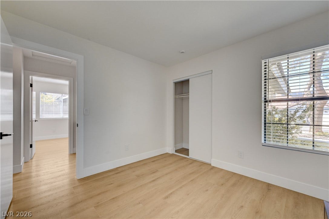 3131 White Rose Way, Henderson, NV 89014 A well-lit bedroom features durable hardwood flooring and a functional sliding closet door.
