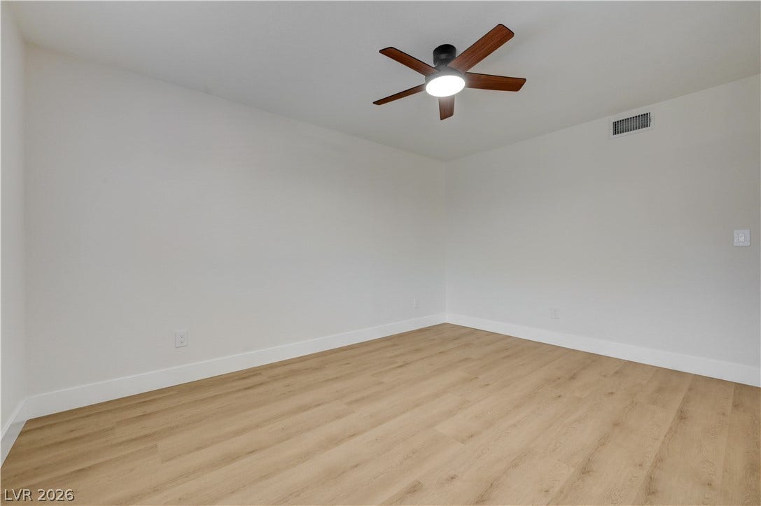 3131 White Rose Way, Henderson, NV 89014 A quiet bedroom featuring light wood-look flooring and a modern ceiling fan.