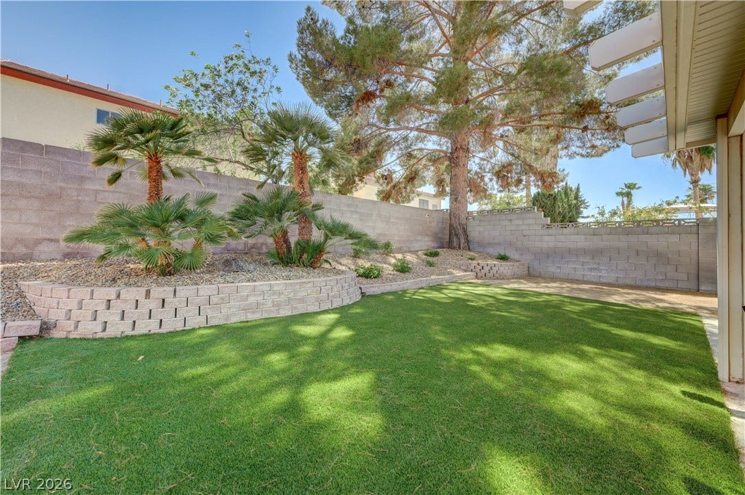 3131 White Rose Way, Henderson, NV 89014 A well-maintained yard provides a tranquil oasis, complete with vibrant green turf and elegant palm plantings.