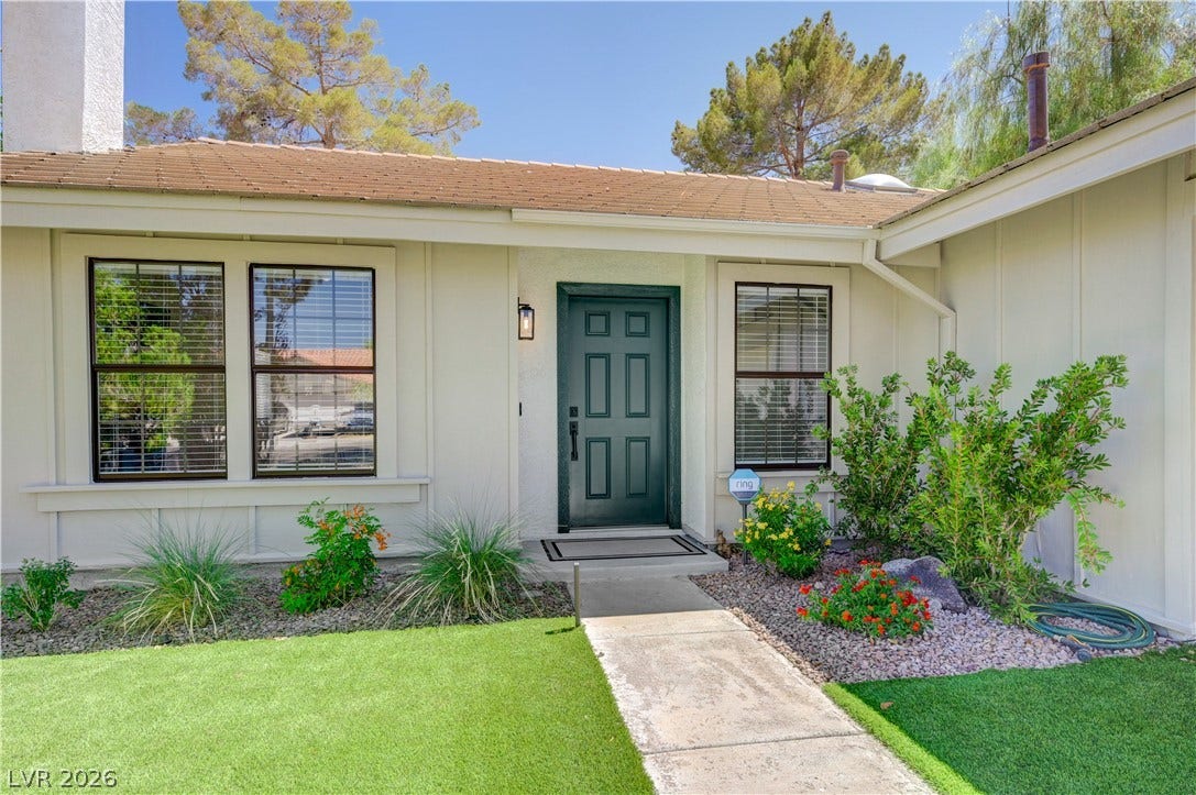 3131 White Rose Way, Henderson, NV 89014 A dark green front door provides a striking contrast to the neutral siding, flanked by neatly maintained landscaping.