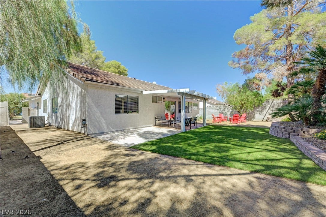 3131 White Rose Way, Henderson, NV 89014 An inviting covered patio opens to a well-kept lawn, ideal for outdoor gatherings.