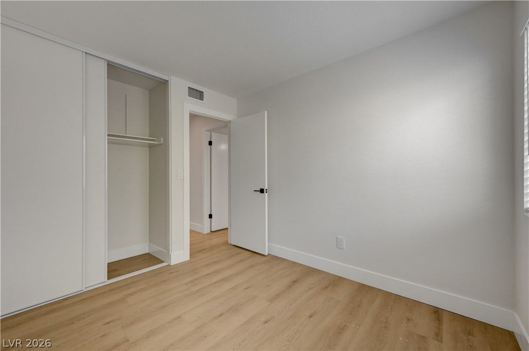 3131 White Rose Way, Henderson, NV 89014 A well-lit bedroom features durable hardwood flooring and a functional sliding closet.