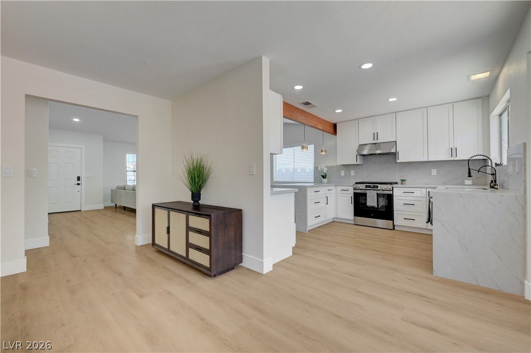 3131 White Rose Way, Henderson, NV 89014 A sleek, contemporary kitchen with pristine countertops and integrated appliances connects seamlessly to a bright living area.