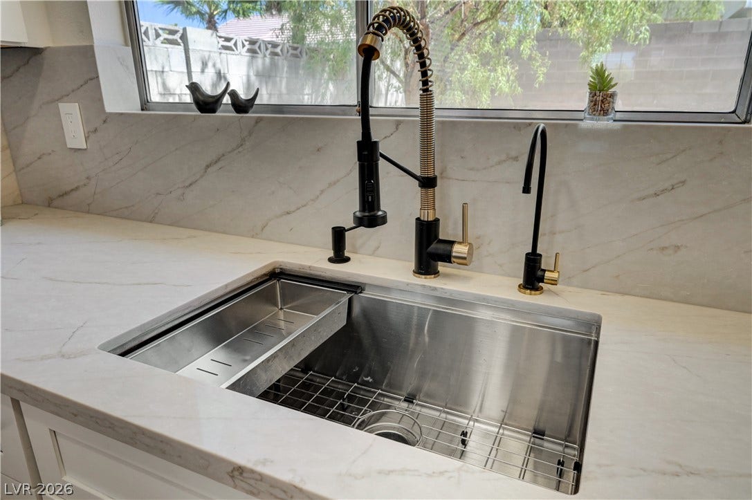 3131 White Rose Way, Henderson, NV 89014 Marble-patterned counters frame a deep, stainless steel sink with a modern black and gold faucet.
