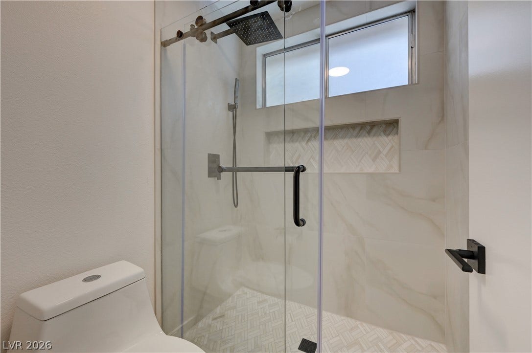 3131 White Rose Way, Henderson, NV 89014 A sleek, contemporary bathroom shower features a glass enclosure, white tile, and a spacious shower niche.