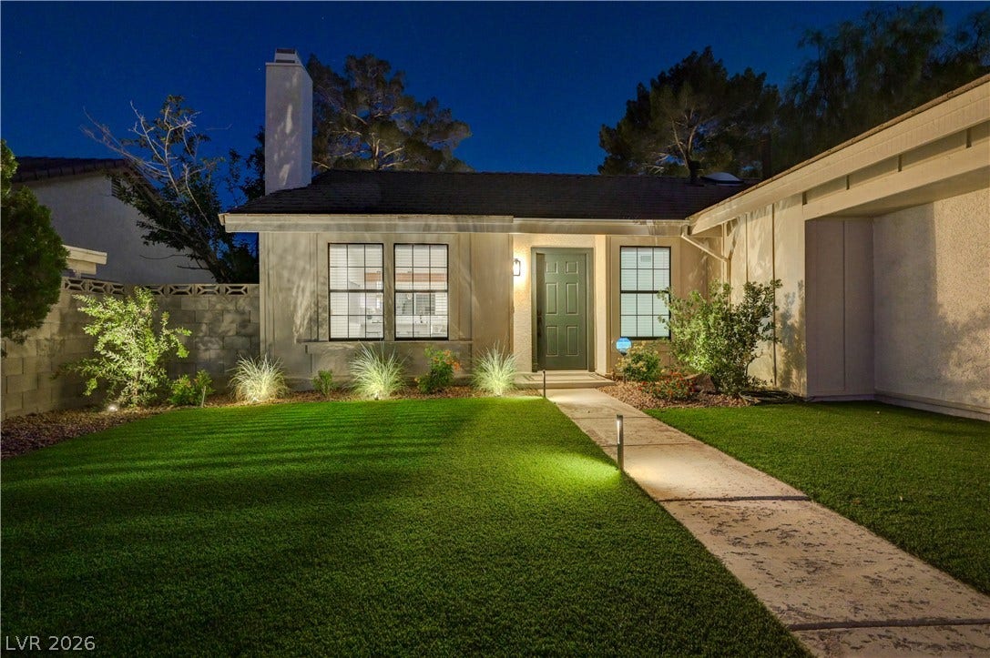 3131 White Rose Way, Henderson, NV 89014 Illuminated walkway and lush lawn enhance this home's inviting evening curb appeal.