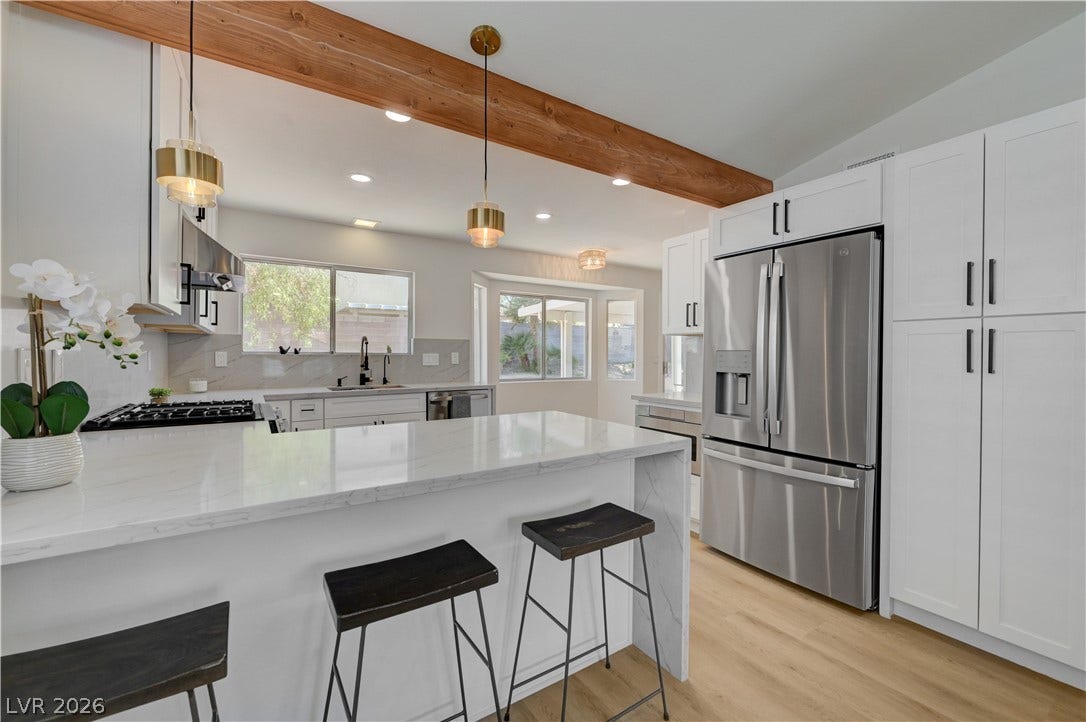 3131 White Rose Way, Henderson, NV 89014 A well-appointed kitchen features stainless steel appliances, a center island with bar seating, and bright windows.
