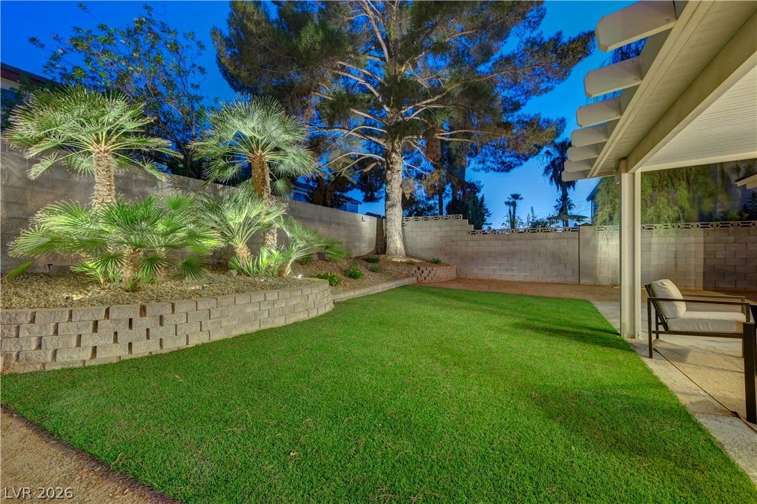 3131 White Rose Way, Henderson, NV 89014 A tiered backyard retreat offers lush artificial turf and mature landscaping, perfect for tranquil evenings.