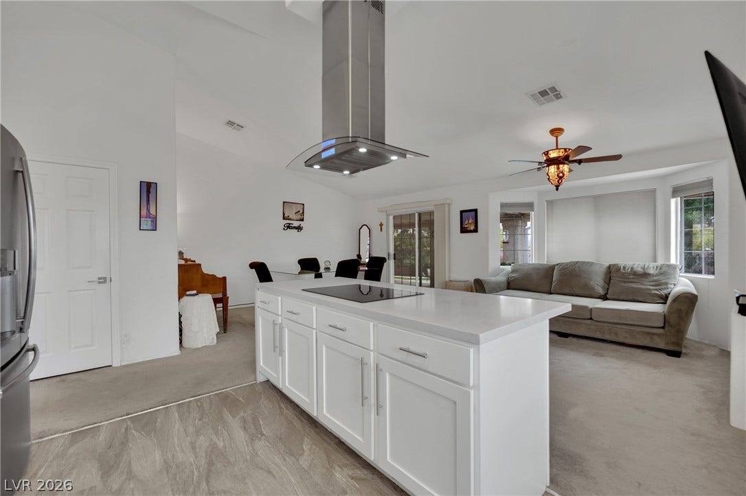 9180 Mohawk Street, Las Vegas, NV 89139 Kitchen with island range hood, stainless steel fridge with ice dispenser, white cabinetry and open floor plan