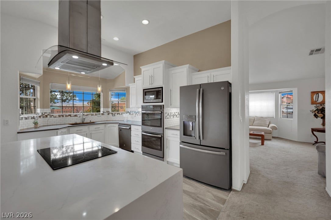 9180 Mohawk Street, Las Vegas, NV 89139 Kitchen featuring white cabinets, plenty of natural light, island exhaust hood, and stainless steel appliances