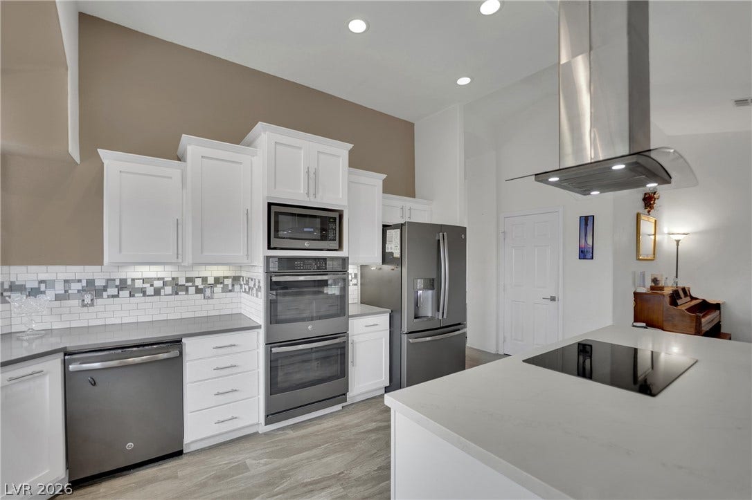 9180 Mohawk Street, Las Vegas, NV 89139 Kitchen featuring island exhaust hood, white cabinetry and stainless steel appliances
