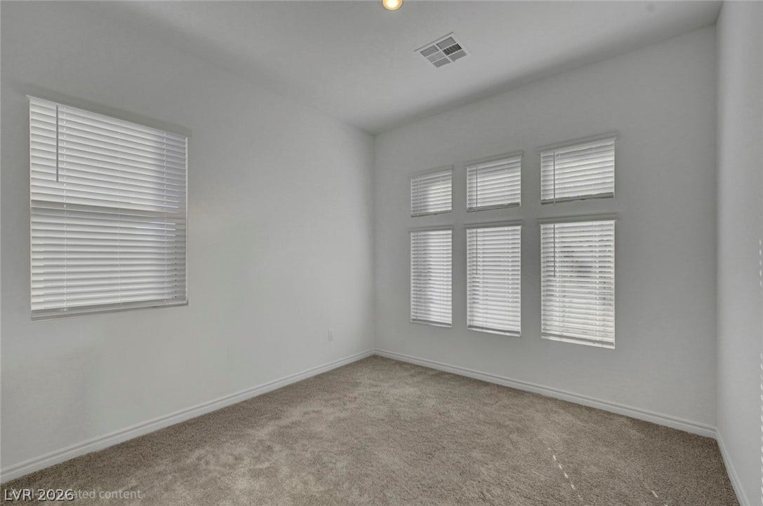 A well-lit, neutral room with fresh carpeting awaits your personalized touch.