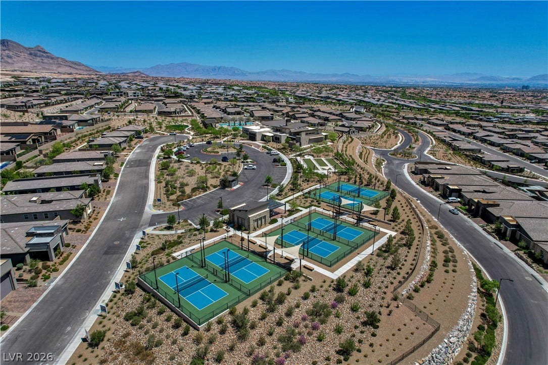 An aerial perspective showcases a vibrant community with recreational courts and well-maintained grounds against a mountain backdrop.