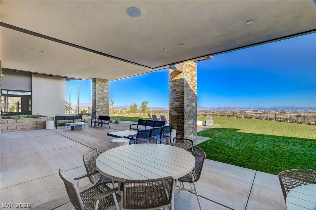 An inviting covered patio area with durable stone accents offers vast scenic views of the city and distant mountains.