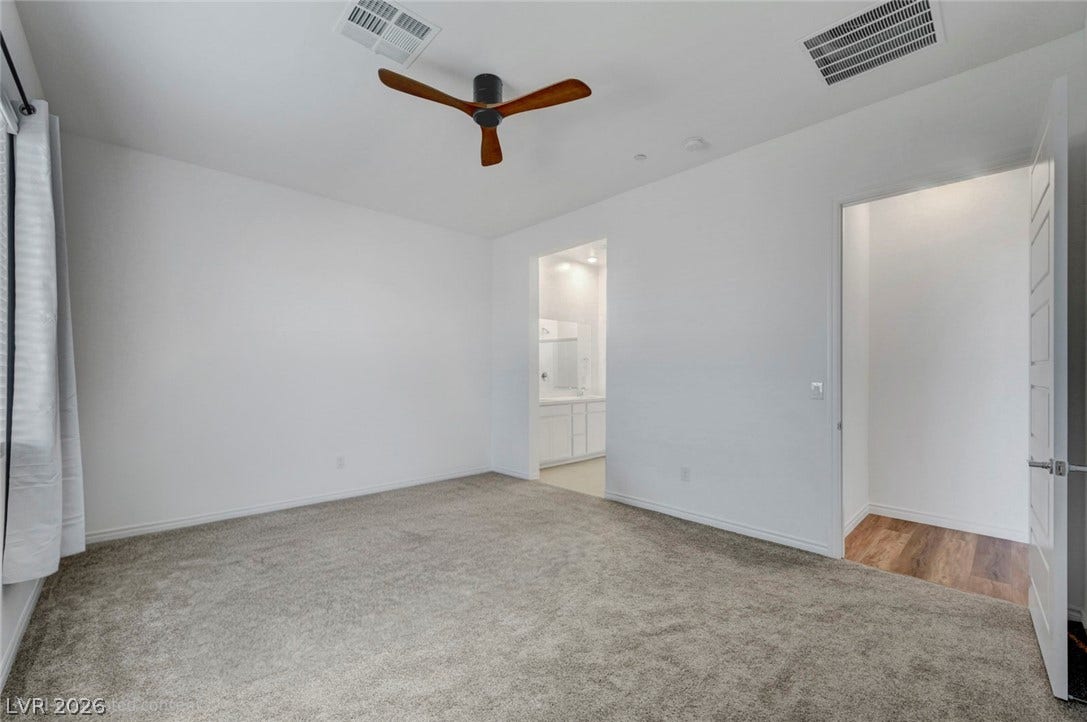 A spacious primary bedroom featuring a ceiling fan and plush carpeting for ultimate comfort.