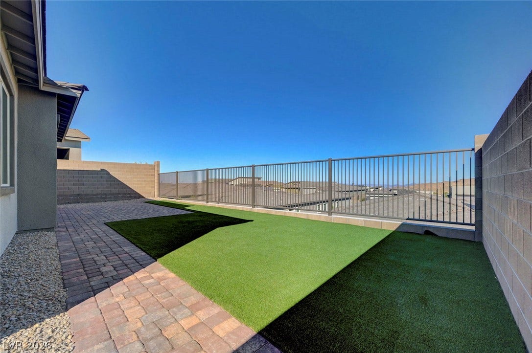 A low-maintenance yard offers both paved patio space and artificial turf for outdoor enjoyment.