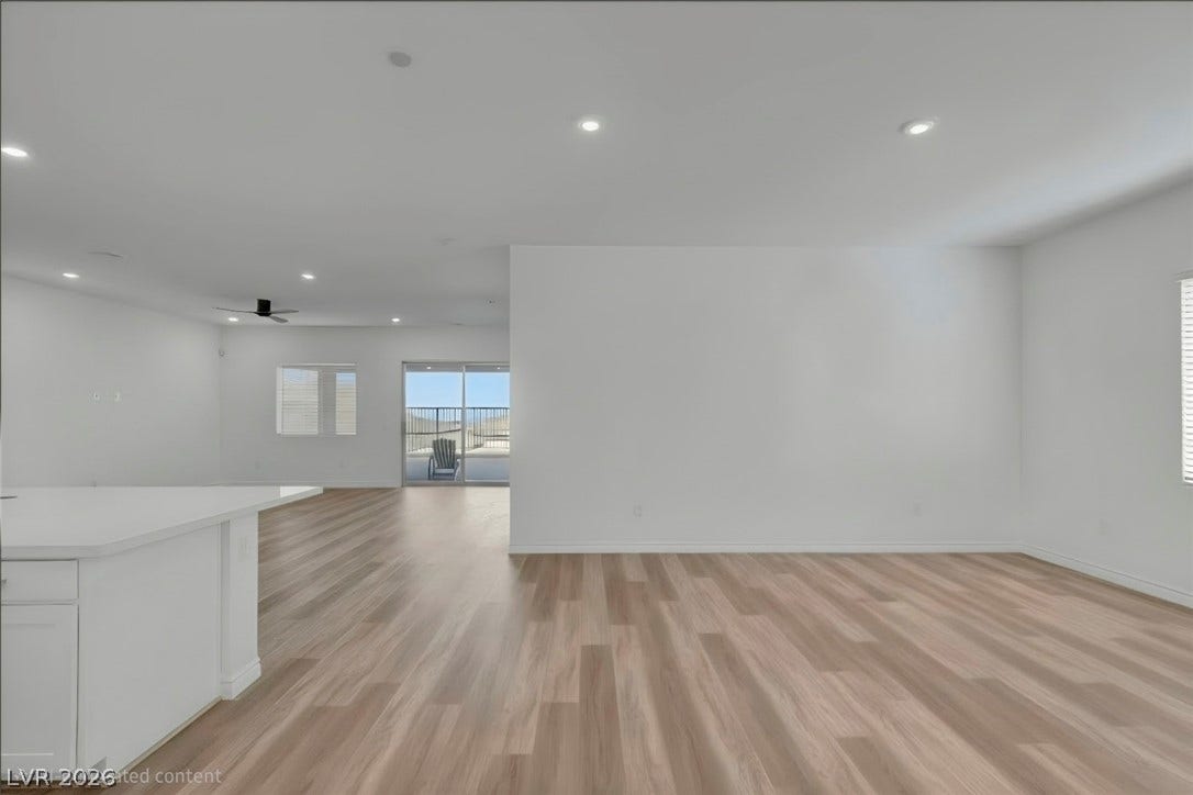 An open floorplan with light wood flooring transitions seamlessly to an outdoor balcony.