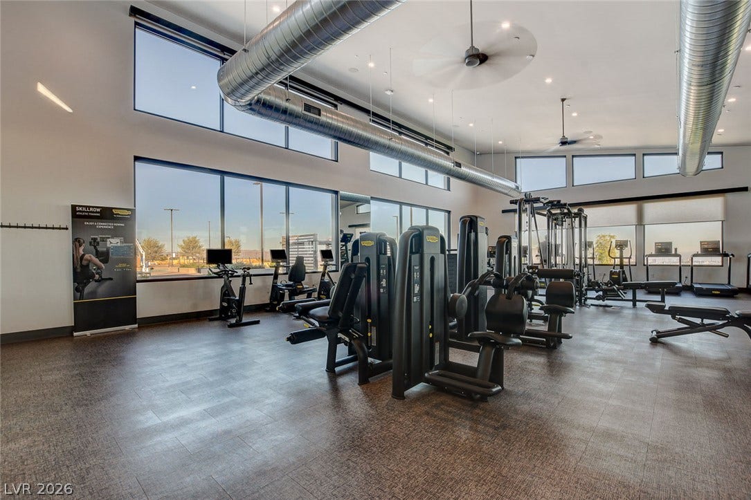Vast windows illuminate this well-equipped fitness center, featuring contemporary workout machines and ample space.