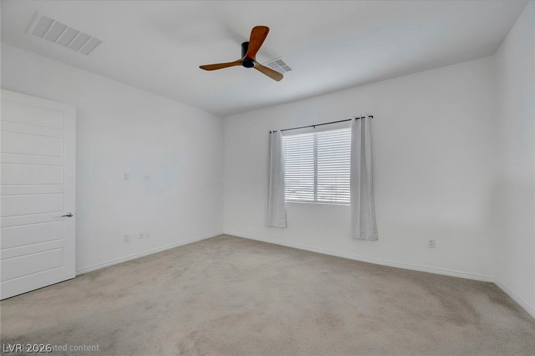 A spacious, naturally illuminated room featuring plush carpeting and a modern ceiling fan for ultimate comfort.