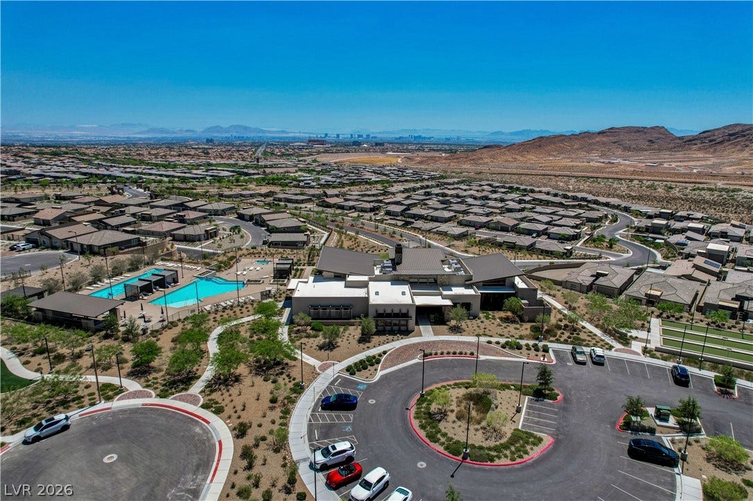An aerial perspective showcases a vibrant community featuring a central clubhouse and sparkling pool, all set against a desert landscape.