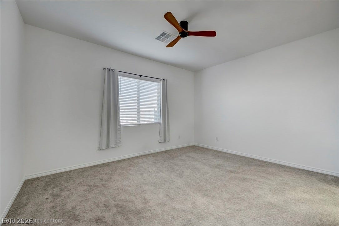 Well-lit room with plush carpeting and a modern ceiling fan, offering a versatile layout.