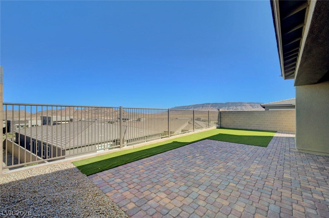 A spacious paver patio and artificial turf create an inviting outdoor living area with mountain views.