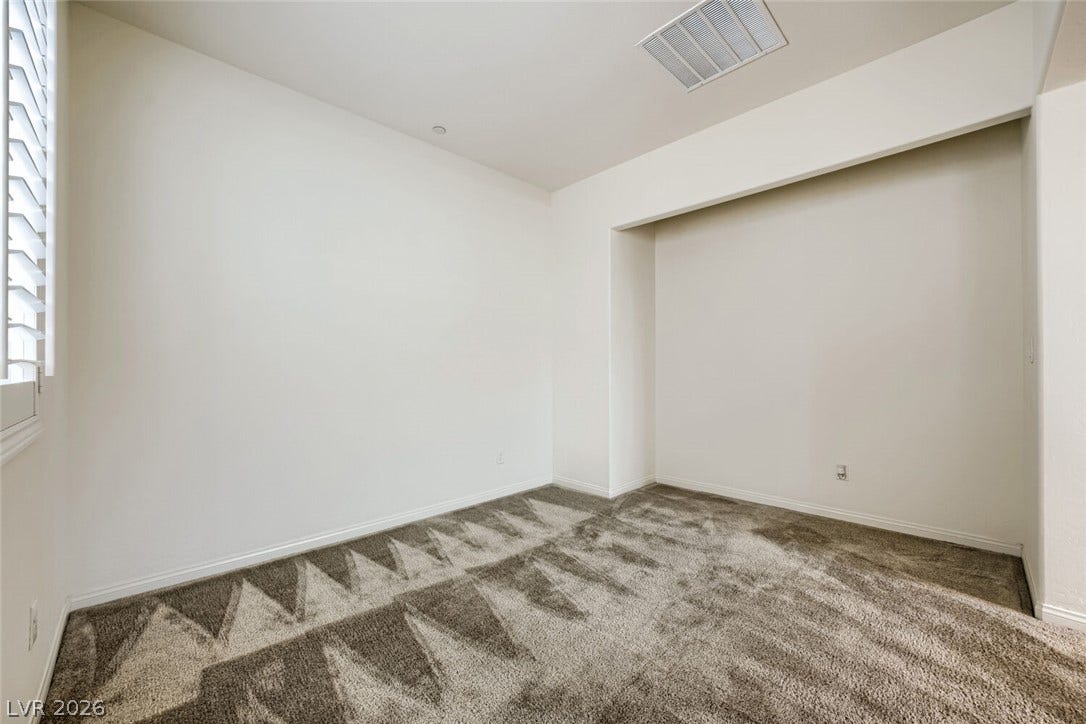 189 Lilt Avenue, Henderson, NV 89011 A spacious room offers comfortable carpet flooring and natural light through louvered window blinds.
