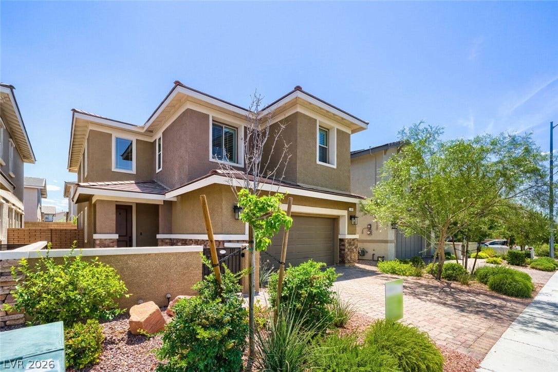 189 Lilt Avenue, Henderson, NV 89011 A contemporary stucco home boasts a paver driveway, attractive landscaping, and an integrated garage.