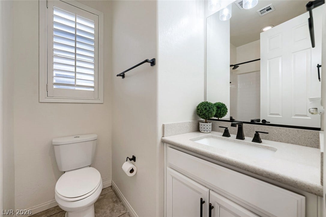 189 Lilt Avenue, Henderson, NV 89011 Refined bathroom with sleek vanity, contemporary fixtures, and shuttered window for privacy.