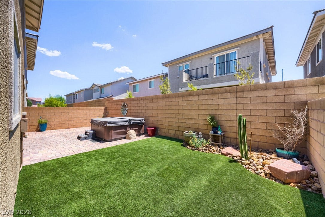 189 Lilt Avenue, Henderson, NV 89011 A well-maintained backyard featuring artificial turf, a paver patio with a spa, and xeriscape landscaping.