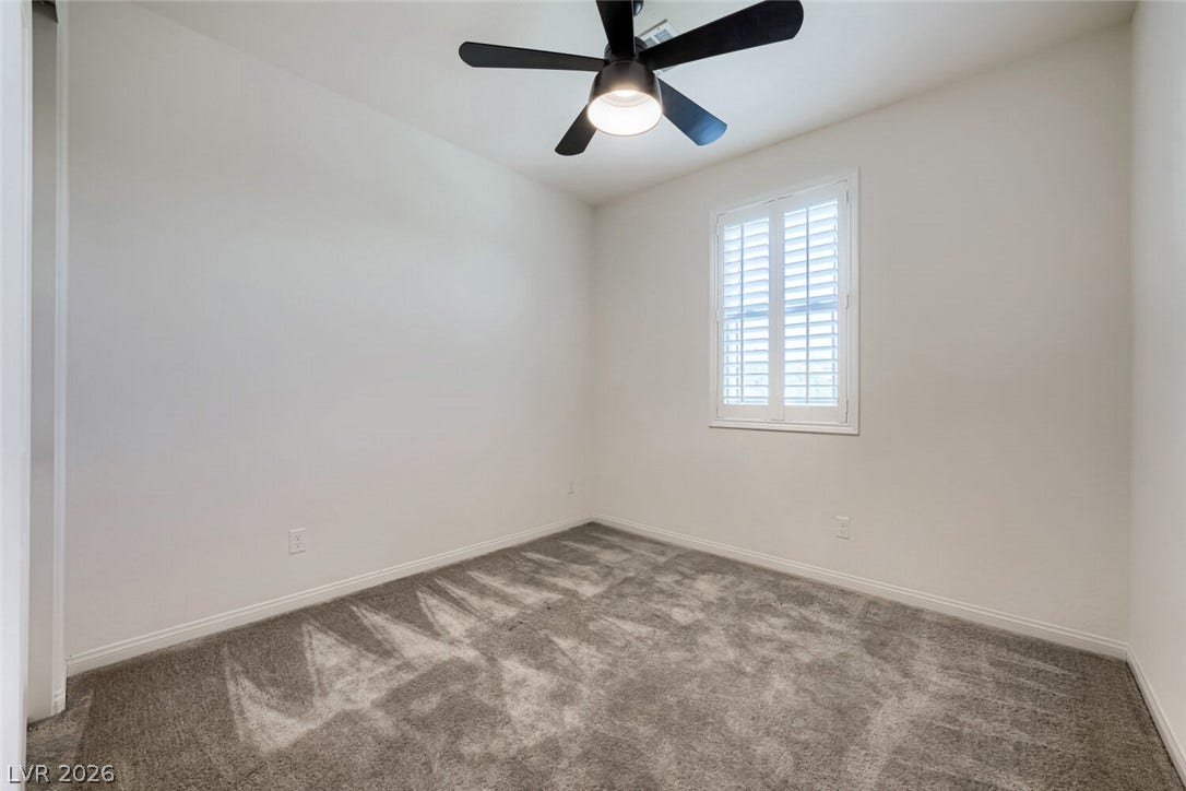 189 Lilt Avenue, Henderson, NV 89011 A well-lit bedroom features plush carpeting and a ceiling fan, offering a comfortable retreat.