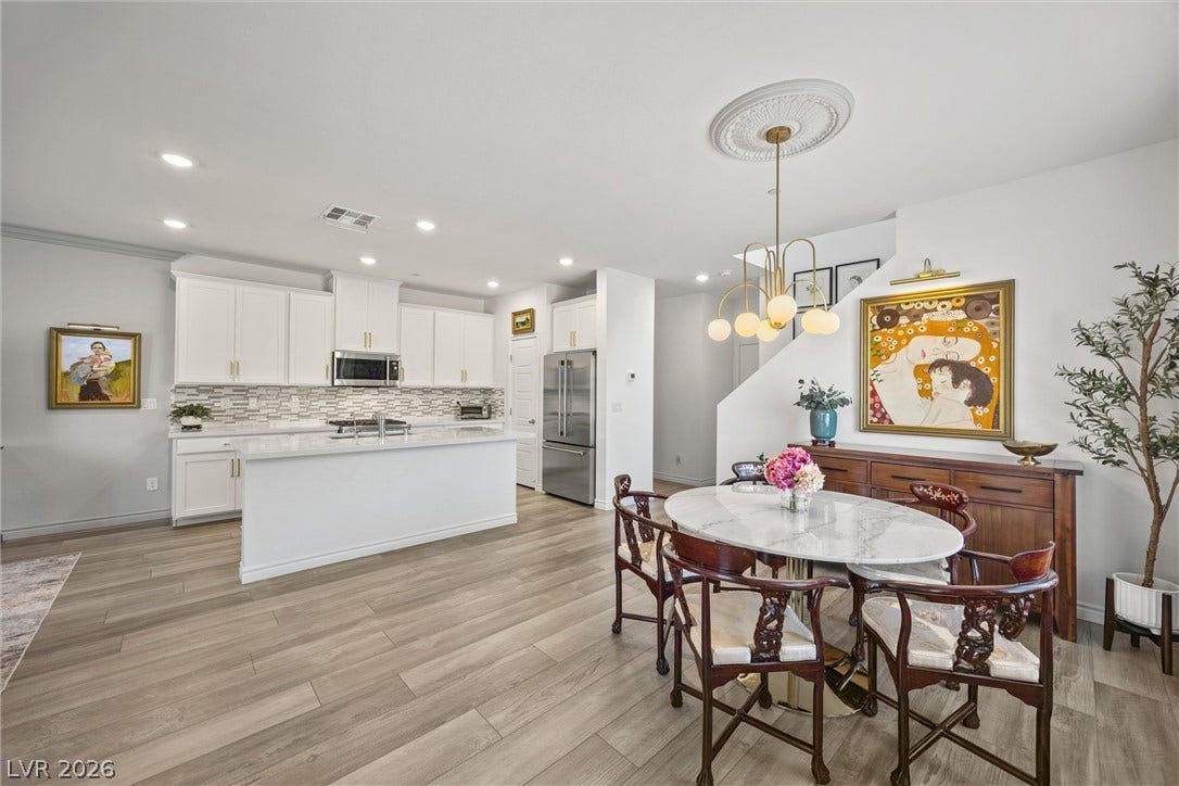 600 N Carriage Hill Drive, #1034, Las Vegas, NV 89138 An open-concept living space integrates a well-appointed kitchen with an elegant dining area, all illuminated by recessed and pendant lighting.