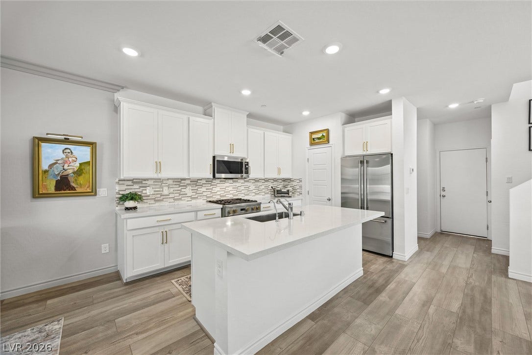 600 N Carriage Hill Drive, #1034, Las Vegas, NV 89138 A contemporary kitchen features bright white cabinetry, a spacious island with a sink, and sleek stainless steel appliances.