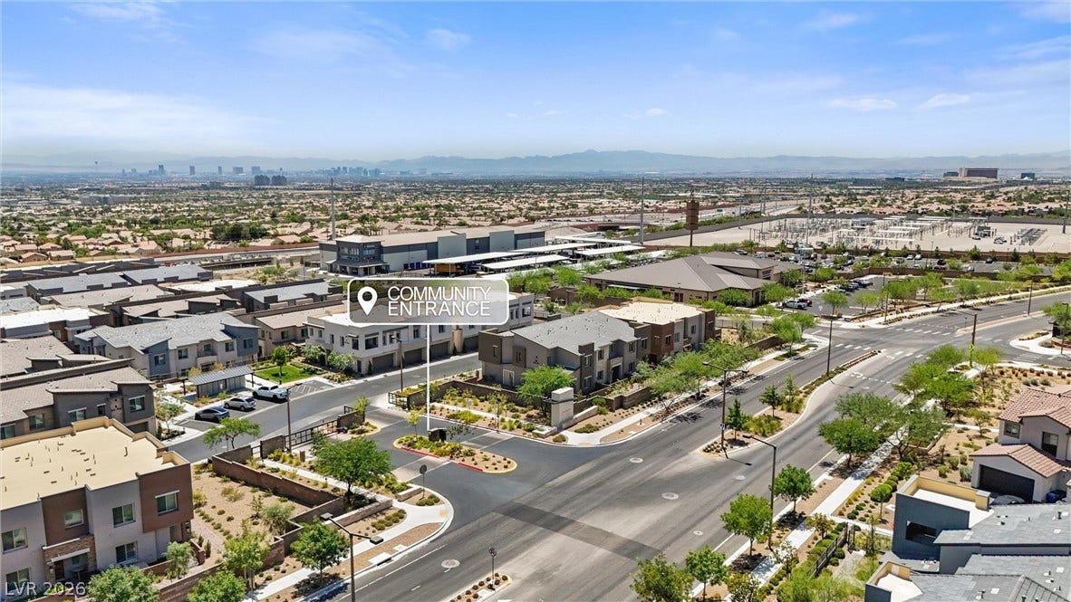 600 N Carriage Hill Drive, #1034, Las Vegas, NV 89138 An aerial perspective reveals a contemporary community entrance leading to modern residences set against a distant cityscape.