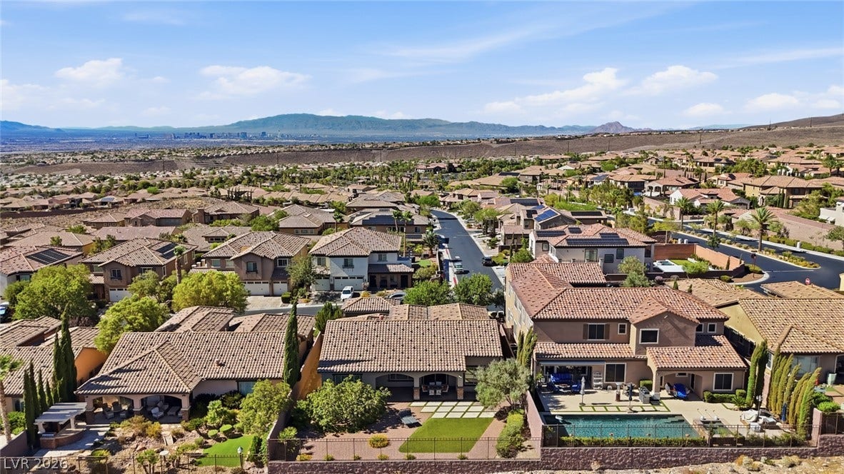 2397 Luberon Drive, Henderson, NV 89044 An aerial perspective reveals a vibrant neighborhood with individual pools, nestled against distant mountains and a bustling cityscape.