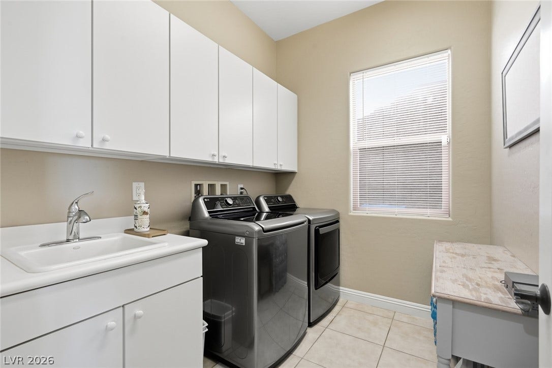 2397 Luberon Drive, Henderson, NV 89044 Functional laundry room equipped with upper cabinetry, a sink, and window blinds for privacy.