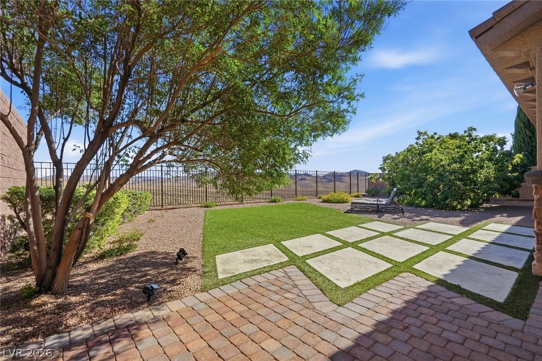 2397 Luberon Drive, Henderson, NV 89044 A tiered outdoor space features brick pavers, concrete squares set in grass, and a distant desert view.