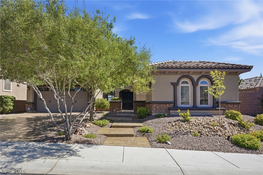 2397 Luberon Drive, Henderson, NV 89044 A graceful home featuring a tiled roof and elegant arched windows, framed by desert-friendly landscaping.
