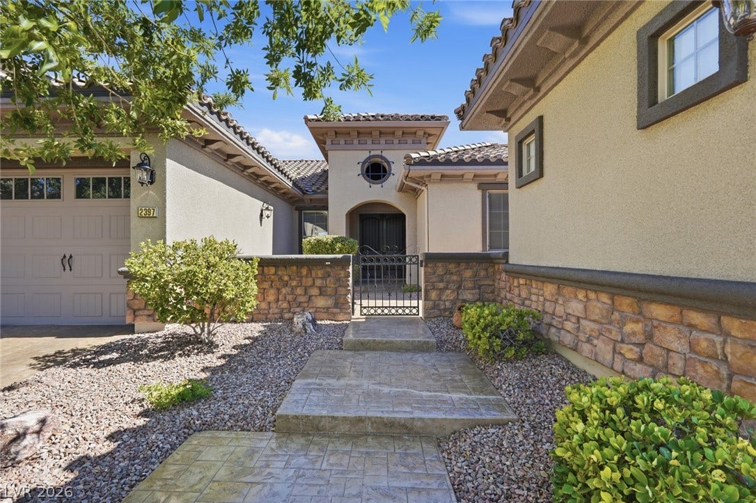 2397 Luberon Drive, Henderson, NV 89044 A welcoming stone walkway leads to a grand entry, complementing the home's stucco and stone facade.