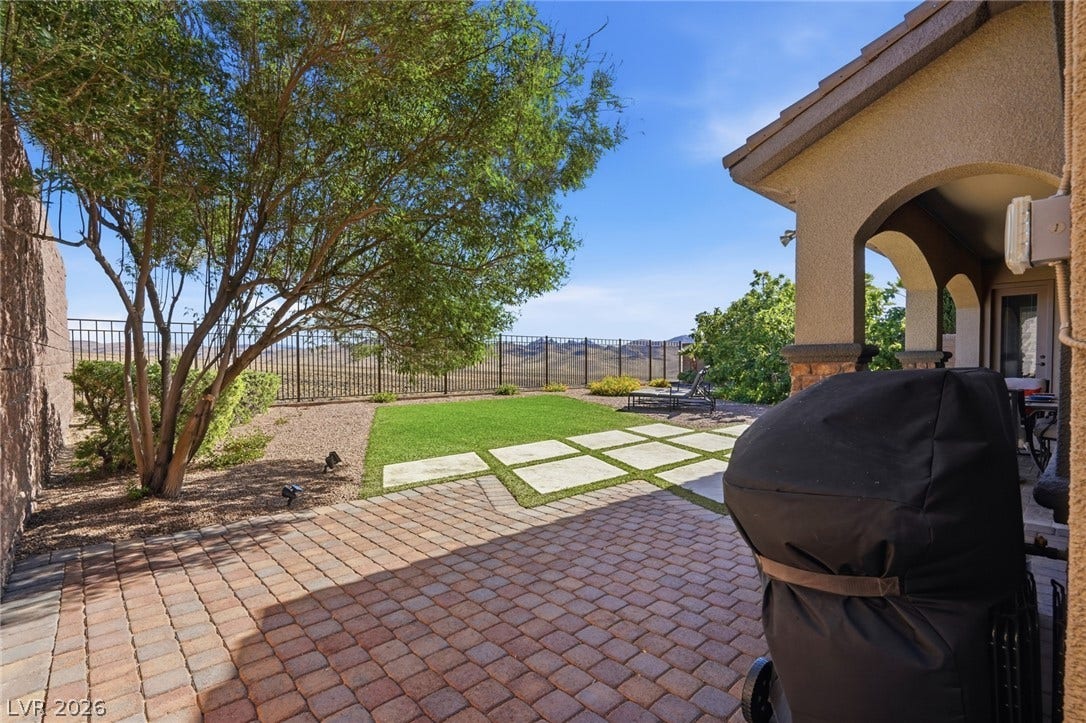 2397 Luberon Drive, Henderson, NV 89044 An inviting paver patio extends to a lush lawn with views of distant mountains under a clear sky.