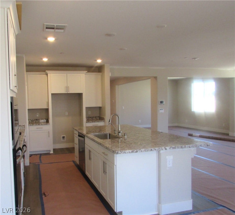 Granite countertops and white cabinetry anchor this spacious, open-concept kitchen. Photo is of actual home.
