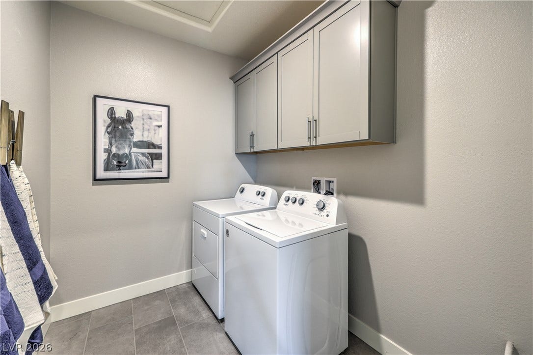 Functional laundry space featuring modern appliances and ample overhead storage cabinetry.