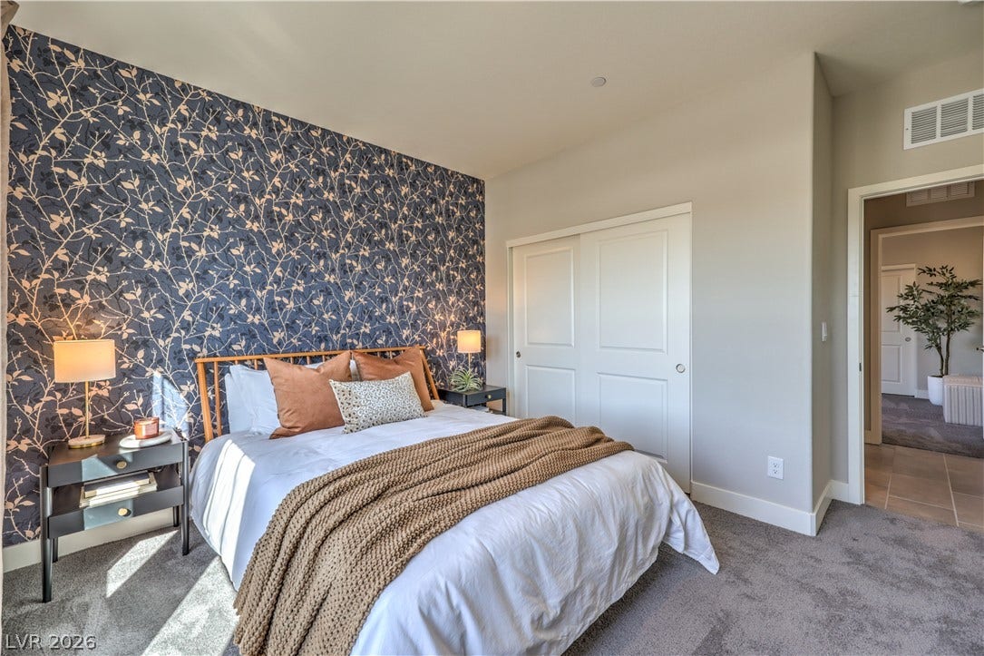 Bold patterned accent wall and soft carpet flooring create a cozy and inviting bedroom retreat.