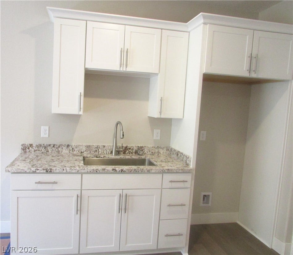 Polished granite countertops and classic shaker cabinetry elevate this functional utility space. Photo is of actual home.